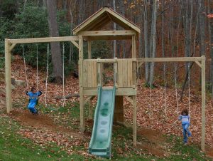 Fort on steep slope with swings and slide - Asheville Playgrounds