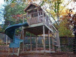 Raised fort with rustic handrails and spiral slide - Asheville Playgrounds