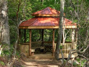 Gazebo in the woods with large cupola, metal roof, and benches all around - Asheville Playgrounds
