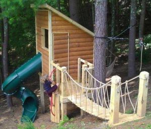 Log cabin with rope bridge and spiral slide - Asheville Playgrounds