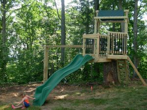 Play set built on a stump using home deck pickets for the railings - Asheville Playgrounds