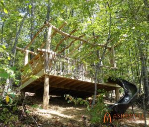 Locust pergola over a large deck in the woods with a slide off the sloped front side - Asheville Playgrounds