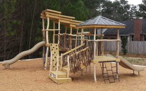 Playground with multiple slides, climbing wall, and rustic features at First Impressions School in Fayetteville, NC - Asheville Playgrounds